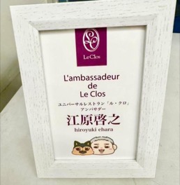 白い木枠に入った認定証。Le Clos のロゴの下に「L'ambassadeur de Le Clos」「ユニバーサルレストラン「ル・クロ」アンバサダー」「江原啓之 hiroyuki ehara」と記され、下にイラストが添えられている。